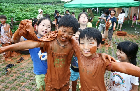 풀무원의 &#039;굿바이 아토피!&#039; 캠프에 참가한 어린이들이 황토 염색 체험을 하며 즐거워하고 있다.