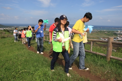 제주도 성산읍 올레길의 말미오름에서 KT 사랑의 봉사단과 부천시 장애인 종합복지관의 지적 장애인이 가족에게 보내는 감사의 편지를 바람개비로 만들어 바람에 실어 보내고 있다.