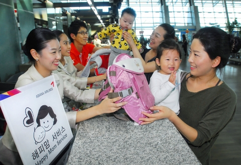 아시아나항공이 10월 1일부터 신설하는 인천공항 유아동반 전용카운터에서 유아동반 승객들이 신속하게 탑승 수속을 받고 기내에서 제공되는 아기띠 사용방법에 대한 설명을 듣고있다.