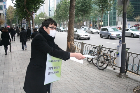 (주)컨퍼넥스 직원이 출근 시간에 플루 확산 방지를 위하여 마스크와 예방 요령이 인쇄된 전단지를 배포하고 있다.