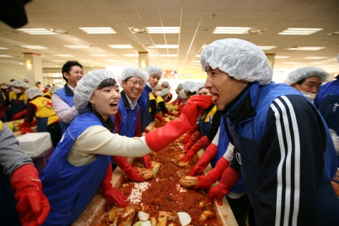 21일 사랑의 김장나누기 행사에 참여한 삼성전자의 한 직원이 프로축구 수원삼성의
중국출신 리웨이펑 선수에게 직접 담근 김장김치를 맛보이는 장면