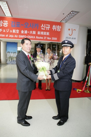 고영섭 제주항공 대표이사가 27일 김포~오사카 노선 첫편의 운항을 담당하는 서효창 기장에게 꽃다발을 전달하고 있다.
