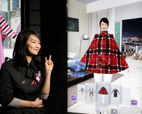 광고모델 신민아 씨가 T.um의 'U.fashion'관에서 만든 자신의 아바타를 보고 밝게 웃고 있다.