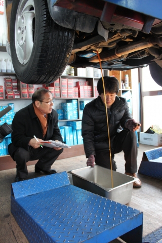 이영철 한국기록원 부원장(사진 왼쪽)이 도전차량의 엔진오일 캡을 제거하고 엔진오일을 빼내고 있다.