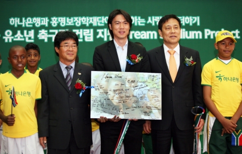 임흥세 감독의 ‘Football Acts 29 남아공 유소년 축구팀‘이 축구장 건립지원 및 축구용품 전달에 대한 감사의 내용이 담긴 보드를 하나은행에 전달함 (좌측부터 임흥세 감독