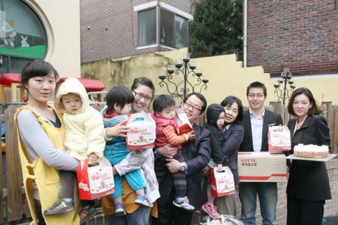 롯데홈쇼핑 직원들이 은평구 물빛어린이집 원장 엄서영 고객과 어린이집을 방문해 어린이들에게 과자선물세트를 전달하고 기념사진을 촬영하고 있다