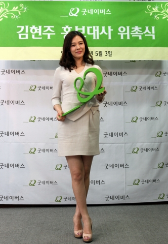 배우 김현주가 ’사랑‘을 의미하는 하트(♡)와 ‘함께’를 의미하는 앰퍼샌드(&)의 조합으로 이루어져 '함께 사랑을 전한다‘는 뜻의 굿네이버스 로고를 들고 있다.
