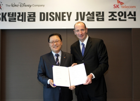 SK텔레콤 정만원 CEO와 월트디즈니 앤디 버드(Andy Bird) 회장이 조인트 벤처 설립에 대한 계약서에 서명한 후 계약서를 펼쳐 보이고 있는 모습