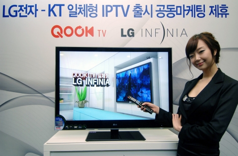 모델이  'QOOK TV 일체형 LG INFINIA'  앞에서 포즈를 취하고 있다.
