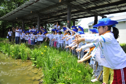 S-OIL 천연기념물 생태체험교실에 참가한 어린이들이 27일 경기도 가평 중앙내수면연구소 내 저수지에 민물고기 먹이를 뿌려주고 있다.