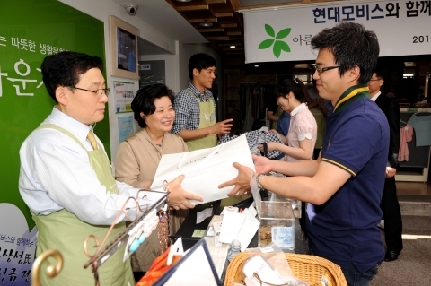 전용덕 이사와 ‘아름다운 가게’ 홍명희 대표, 우지원 선수가 카운터에서 물품구매 고객의 계산을 돕고 있다.
