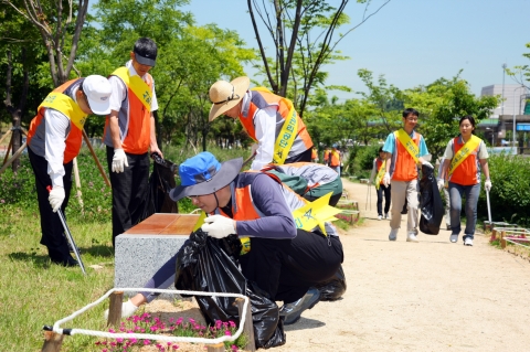 화정천 옆 공원길을 따라 안산시시설관리공단 임직원이 환경정화활동을 펼치고 있다.