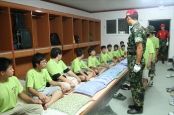 Primary school students who participated in the Marine Crops Camp are taking evening roll calls from an instructor after finishing exercises.