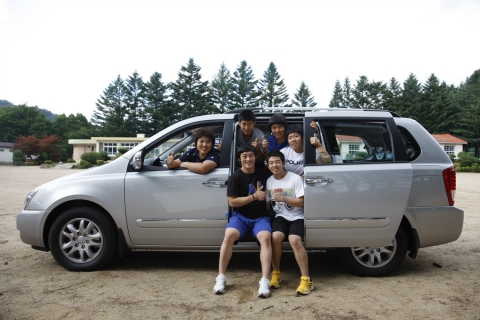 강원도 평창에 위치한 진부중고등학교의 역도부 5총사가 학교 운동장에서 선물 받은 기아차 그랜드 카니발과 함께 사진 촬영을 하는 모습