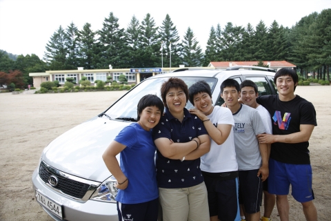 강원도 평창에 위치한 진부중고등학교의 역도부 5총사가 학교 운동장에서 선물 받은 기아차 그랜드 카니발과 함께 사진 촬영을 하는 모습