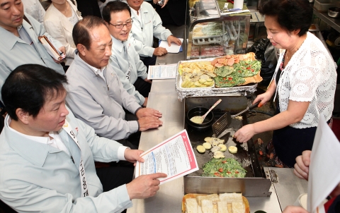 최태원 SK그룹 회장(왼쪽)과 김승유 미소금융중앙재단 이사장(왼쪽 두번째), 정만원 SK텔레콤 사장(왼쪽 세번째)이 7일 서울 종로구 광장시장의 한 모듬전 가게에 들러 상인에게 미