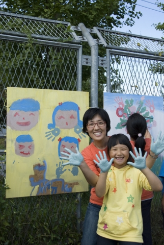 샘표 간장공장에서 열린 &#039;수확하는 예술가&#039;행사에 참여한 가족, 손으로 그린 벽화를 배경으로 가족이 환하게 웃고 있다.
