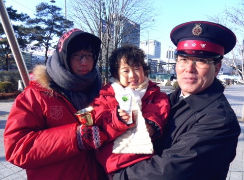 12월 15일 서울 광화문 자선냄비 앞에서 영하 10도의 날씨 속에서도 어려운 이웃을 위해 모금 운동을 하고 있는 봉사자에게 구세군 자원봉사 어린이가 화장품을 전해주고 있다.