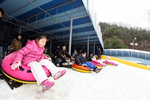 아이들이 슬로프 출발 대기장소에서 출발신호와 함께 썰매를 타며 즐거워하고 있다.