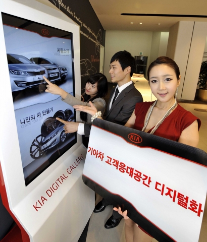 디지털 사이니지가 적용된 기아차 지점에서 고객들이 인터랙티브 터치 스크린 ‘기아 디지털 갤러리(Kia Digital Gallery)’를 작동해 차량 정보를 보는 모습.