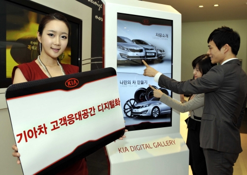 디지털 사이니지가 적용된 기아차 지점에서 고객들이 인터랙티브 터치 스크린 ‘기아 디지털 갤러리(Kia Digital Gallery)’를 작동해 차량 정보를 보는 모습.