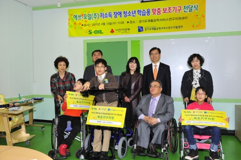 S-OIL 류열 CFO(뒷줄 오른쪽 2번째)가 13일 경기도 수원시 재활공학서비스연구지원센터에서 오길승 센터장(앞줄 오른쪽 2번째)이 참석한 가운데 장애 청소년들에게 학습용 맞춤 보조기구 전달식을 가졌다.