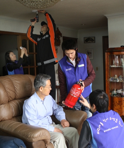 29일, 현대백화점 압구정 본점 직원들과 강남소방서 소방대원이 방죽마을의 한 가정을 방문하여 화재경보기를 설치하고 소화기 사용법을 안내하고 있다.