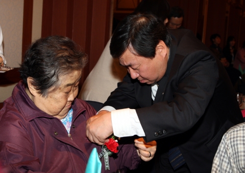 독거어르신에게 사랑의 카네이션을 달아드리는 모습