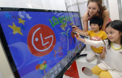LG전자 홍보도우미와 어린이들이 함께 LG PDP 펜터치 TV에 그림을 그리고 있다