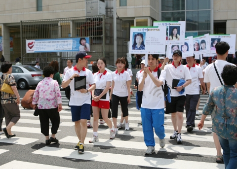 KT 블루보드 회원들이 영등포 역앞에서 미아들의 정보가 담긴 피켓 및 아이패드를 들고 시민들에게 설명하고 있다.