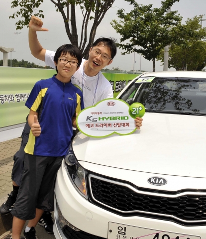 기아차는 23일(토) ‘K5 하이브리드’의 우수한 연비를 널리 알리기 위해 ‘K5 하이브리드 에코 드라이버 선발대회’를 개최했다. 이번 대회에서는 김의중 씨(43세)가 최고 연비인 28.6km/ℓ로 1위를 차지했으며 탁용진 씨(28세)와 권석기 씨(33세)가 27.9km/ℓ를 기록했으나 주행시간에서 탁용진 씨가 2분 앞서 각각 2위와 3위를 차지했다. 사진은 1위한 김의중 씨가 아들과 함께 포즈를 취하고 있는 모습.