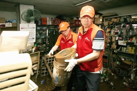 김신배 SK자원봉사단장(SK그룹 부회장, 사진 왼쪽)과 윤진원 SK(주) 윤리경영부문장(사진 오른쪽)이 지난 30일 경기도 동두천시 수해지역의 한 상점에서 복구작업을 돕고 있다.