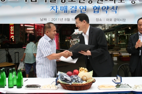 - 중소기업기술정보진흥원 윤도근 원장이 전통시장 활성화를 위해 지난 8월 18일 개최한 마포 공덕시장과의 자매결연 협약식에서 마포공덕시장 상인회장과 협약서를 교환하고 있다. (좌, 마포공덕시장상인회 박종서 회장 / 우, 중소기업기술정보진흥원 윤도근 원장)