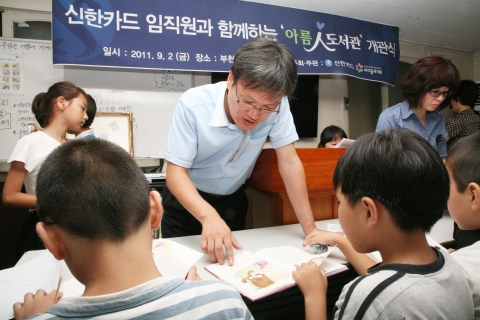 신한카드는 2일 오후 부천지역아동센터에서 아름인 도서관 개관식을 갖고 봉사활동을 펼쳤다. 신한카드 이기봉 부천지점장이 아이들과 함께 티셔츠에 그릴 그림을 고르고 있다.
