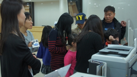 입장객들이 관람후 전시장 입구에 설치된 셀프 사진앨범제작코너에서 사진작가가 찍어준 사진작품의 인화서비스를 받기위해  기다리고 있다