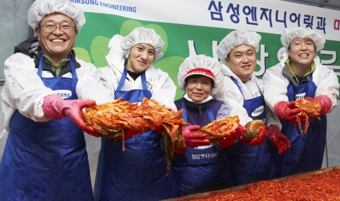 삼성엔지니어링 임직원들과 안성 미리내 마을 주민들이 함께한 ‘사랑의 김장 담그기’행사에서 담근 김치를 내밀며 활짝 웃고 있다.