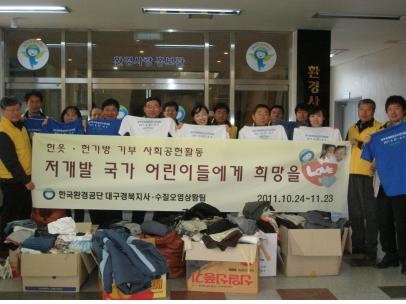 한국환경공단 대구경북지사 직원들이 기부할 대구세계육상선수권대회 홍보용 티셔츠를 들고, 모아진 옷과 가방 앞에서 기념촬영을 하였다.