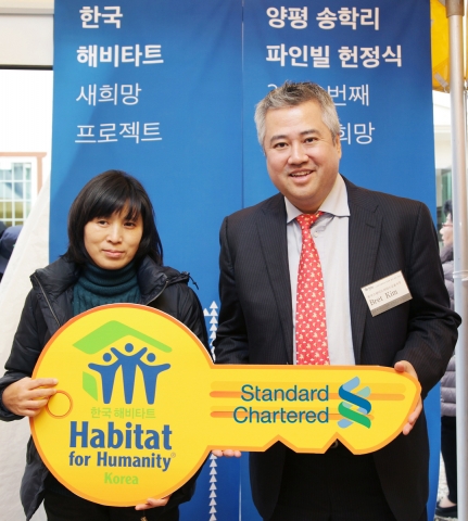 한국스탠다드차타드금융지주 전략부서를 총괄하고 있는 브렛 김(Bret Kim)부사장이 2일 경기도 양평 송학리 파인빌에서 2000번째 집 홈파트너에게 열쇠를 전달하고 기념촬영을 하고