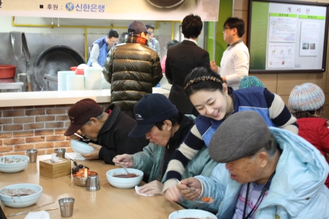 강서노인종합복지관에서 신한은행 자원봉사자들이 어르신들에게 동지팥죽을 대접하고 있는 모습