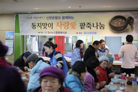 강서노인종합복지관에서 신한은행 자원봉사자들이 어르신들에게 동지팥죽을 대접하고 있는 모습