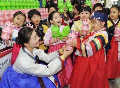 아시아나항공(대표 윤영두)이 임진년 설 연휴기간을 맞아 19일(수) 김포공항 국내선 청사에서 귀성객들에게 용 모형 저금통 증정행사를 가졌다. 한복을 입은 아시아나항공 공항 여직원(왼쪽)이 어린이에게 저금통을 선물하고 있다.