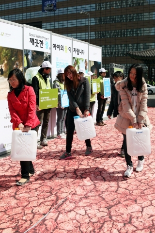 21일(수), 국제구호개발 NGO 굿네이버스 주최로 진행된 &#039;세계 물의 날&#039; 캠페인에서 시민들이 물부족 국가 현지 아동 체험으로 물통을 들고 길을 걷고 있다.