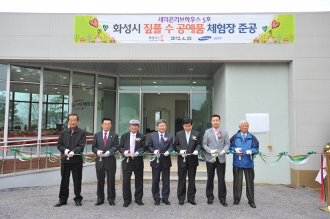 삼성전자 DS부문 사회봉사단은 25일(수) &#039;세미콘 러브하우스 5호 - 짚풀 수공예품 체험장&#039;을 화성시 &#039;우리꽃 식물원&#039;(팔탄면 소재) 내에 건립하여 화성시에 기증하는 준공식 행사를 가졌다. 참석자들이 테이프 커팅을 하고 있다.