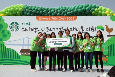 스타벅스커피 코리아 이석구 대표이사가 5월 6일 여의도 한강공원에서 자선 마라톤을 개최하고 초록우산 어린이 재단의 김미경 본부장에게 드림 오케스트라 지원 기부금을 전달하고 있다.