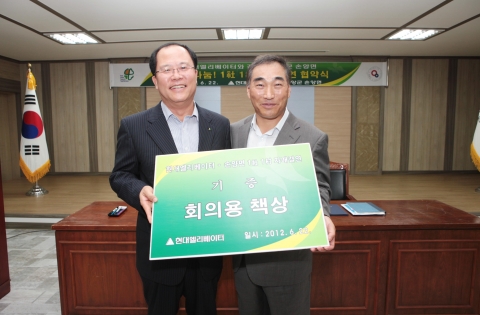 일사일촌 자매결연 협약식에서 현대엘리베이터 한상호 대표(사진 왼쪽)가 손양면장에게 기증품을 전달했다.