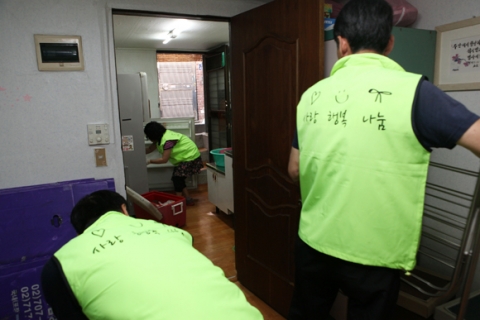 봉사자와 이삿짐 직원들이 이사를 위해 땀방울을 흘리고 있다.
