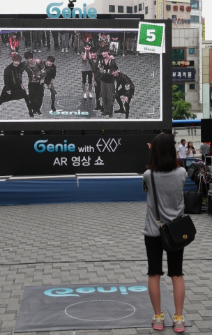 지난 5월 대전 은행동에서 진행했던 ‘지니 AR영상쇼’에 참가한 고객이 증강현실 속의 엑소케이(EXO-K)와 포즈를 취하고 있다.