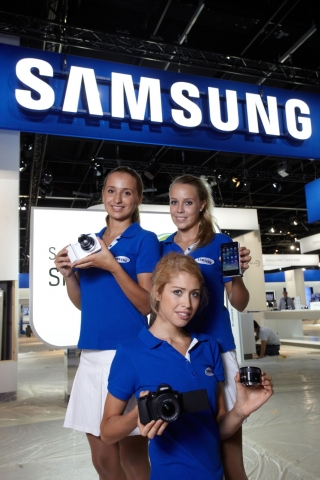 포토키나 전시장 쾰른 메세 Hall 5.2에 있는 삼성전자 부스에서 모델들이 갤럭시 카메라(사진 좌, 우)와 NX 시리즈 카메라, 렌즈(사진 중앙)를 선보이고 있음.