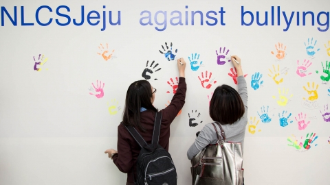 NLCS Jeju의 재학생들이 교내에 마련된 ‘서약의 벽’에 집단 따돌림을 하지 않겠다는 서명을 하는 핸드프린트 행사에 참여하고 있다. NLCS Jeju는 교내 집단 따돌림을 사전
