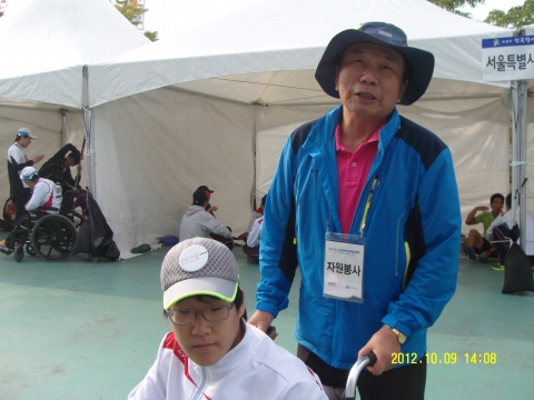육상경기장 안내소에서 만난 1:1봉사자 김종환씨가  서울특별시 선수단의 김민석 선수(육상의 던지기-원반, 포환, 창)를 도와주고 있다.